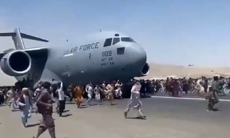 People run after and cling to a moving US military plane leaving Kabul airport.