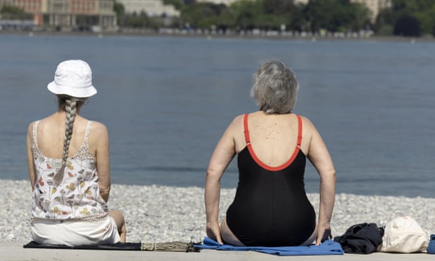 Two women sit on a beach in Geneva, Switzerland