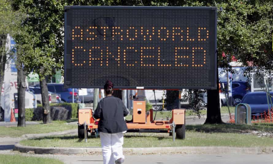 A pedestrian cross Main Street in front of a sign announcing the cancellation of Astroworld