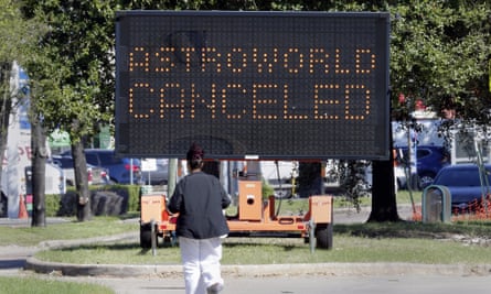 A pedestrian cross Main Street in front of a sign announcing the cancellation of Astroworld