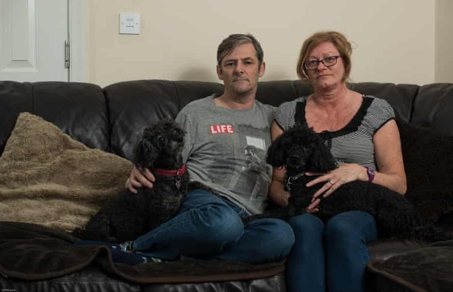 stephen and angela bullough sitting on the sofa with their two dogs at home in wigan lancs