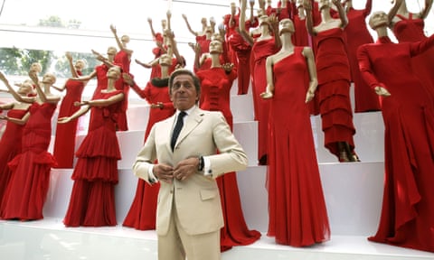 Valentino Garavani stands before a collection of mannequins in red dresses