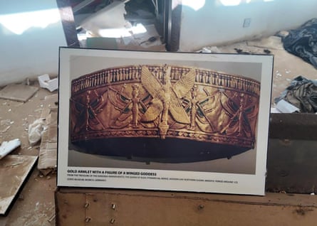 A photo of a golden armband in a room full of debris