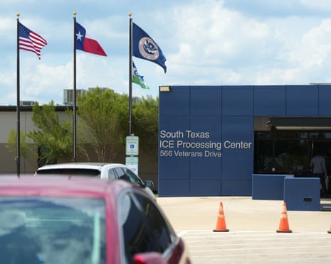 Flags outside the an ICE processing center with cars parked nearby