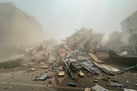 People inspect the debris of a collapsed building in Mandalay on 28 March 2025, after an earthquake.