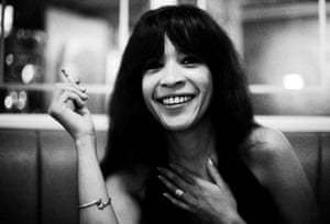 A black and white portrait of a woman with long bangs holding a cigarette