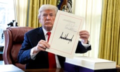 A man holds up a sheet of paper that he signed