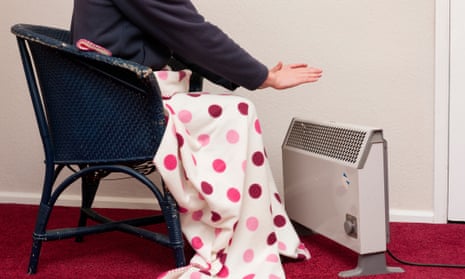 Person in fleece jacket sitting under blanket next to old electric heater