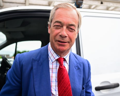 Farage in a blue suit and red tie stands beside a car door