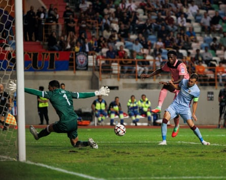 Jules Ahoka shoots and scores past a diving goalkeeper during a football match