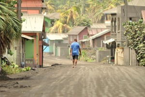 Volcanic ash covers St Vincent – in pictures 4 A man walks down an ash-covered street in Georgetown.
