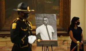 A state trooper stands next to a picture of the late congressman John Lewis in Atlanta