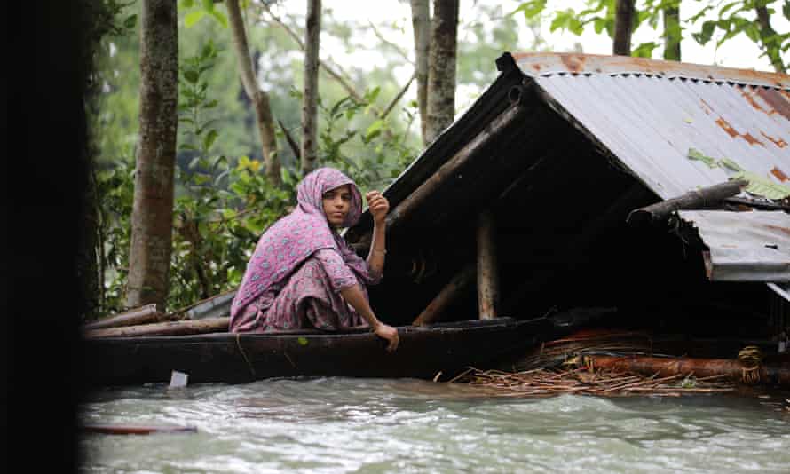 A woman is seen on a boat in front of her submerged house