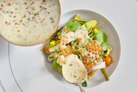 A picture of a green salad topped with caviar in a white dressing.