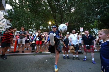 A Scotland instrumentality wearing a kilt plays shot successful a thoroughfare successful Boston earlier the lucifer against Haiti.