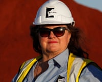 Gina Rinehart in hardhat in front of mound of iron ore