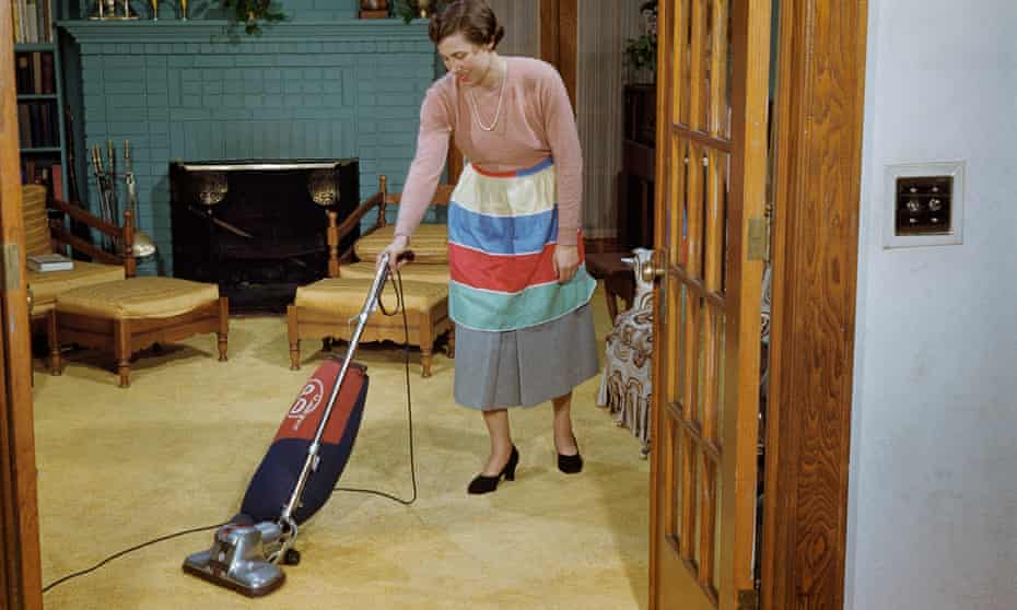 1953 photo of woman vacuuming a living Room.