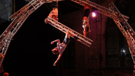 Members of the Aloft company hang from an arch made of ladders