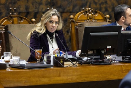 A middle-aged woman sitting at a table with a computer in a parliament
