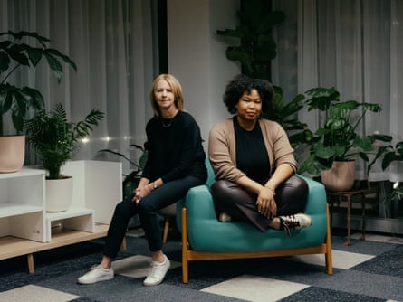 research project online advertising A white woman and a Black woman sit back on a teal armchair.