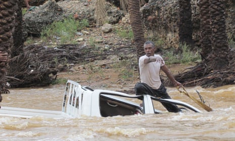 A man tries to save a vehicle being swept away by flood waters in the Yemeni island of Socotra