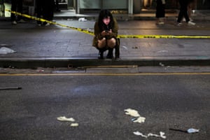 Woman crouching using phone by police tape