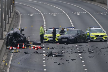 Damaged cars and police cars and three people looking at them