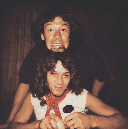 Two men smile, one resting his head atop the other’s