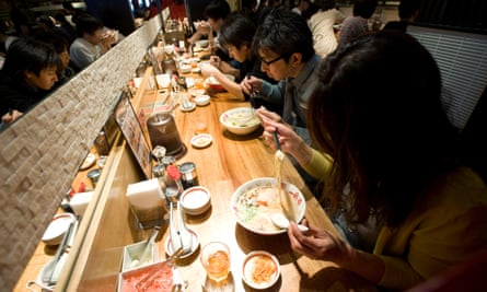 People eating ramen at a counter bar 