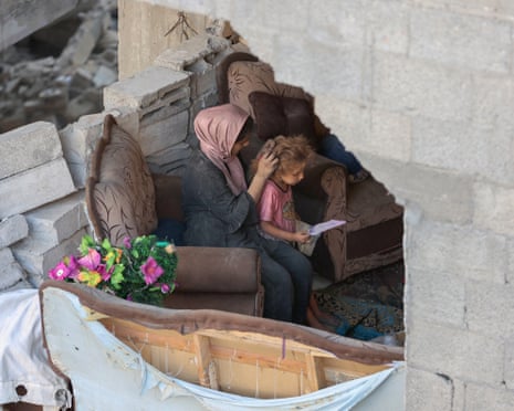 A Palestinian woman ties her daughter's hair after an Israeli strike on the Al-Shati refugee camp, west of Gaza City.