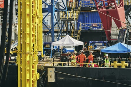 a crew of workers watches a vertical injector while aboard a barge