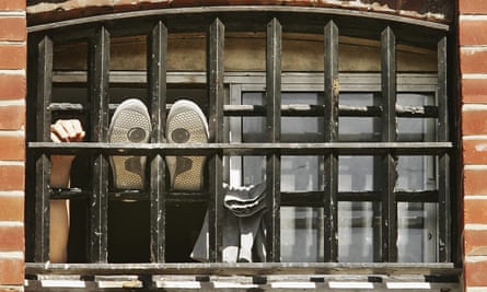Man sticking feet onto bars of prison window