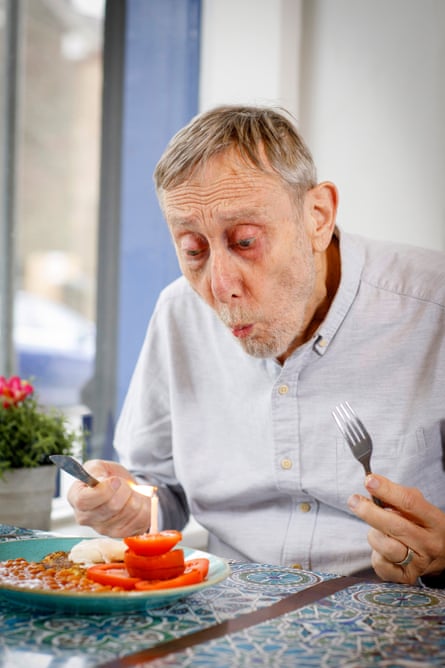Michael Rosen with raised knife and fork looking excited about eating a plate of beans, eggs and tomatoes