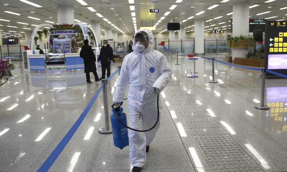 A worker in protective gear carries a disinfectant spray can at the Pyongyang airport. 