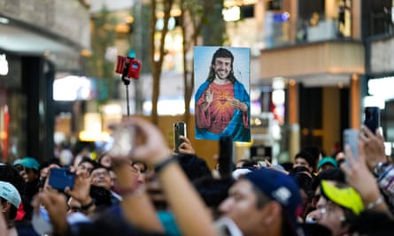 A fan holds a poster depicting Fernando Alonso as the Most Sacred Heart of Jesus during a promotional event in Mexico City