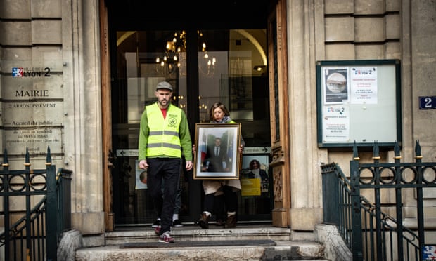 Activists leave with a portrait from a town hall in Lyon.