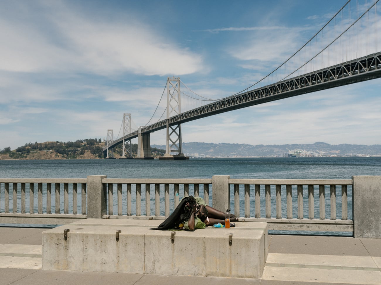 A woman lies on a block along the Embarcadero across from Google’s satellite office in downtown San Francisco.