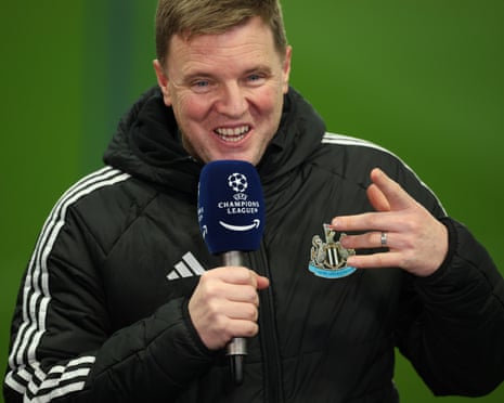 Newcastle United manager Eddie Howe smiles and makes a gesture with his hand as he speaks into a microphone whilst being interviewed.