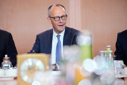 Friedrich Merz smiling while sat at a large table