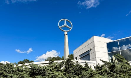 A gleaming white Mercedes automotive plant, fronted by a Mercedes symbol on a pillar
