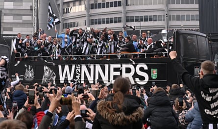 Kieran Trippier holds the Carabao Cup trophy aloft with Alexander Isak on board the open top bus with their teammates and manager Eddie Howe (front row, left) as they pass St James’ Park.