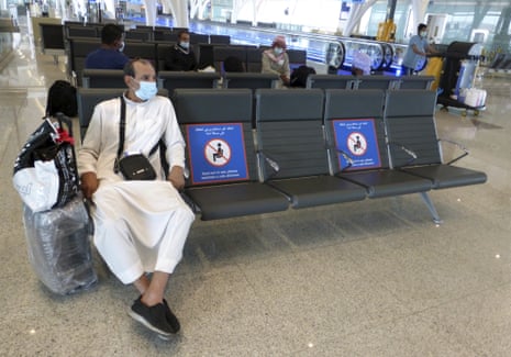 A passenger sits beside posters displaying social distancing restrictions as he waits for his flight at the King Abdulaziz International Airport in Jiddah, Saudi Arabia, on 28 July 2020. The authorities have eased domestic travel restrictions since June.