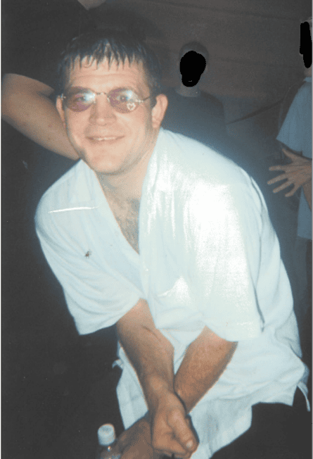 A man wearing a white shirt and sunglasses in a nightclub