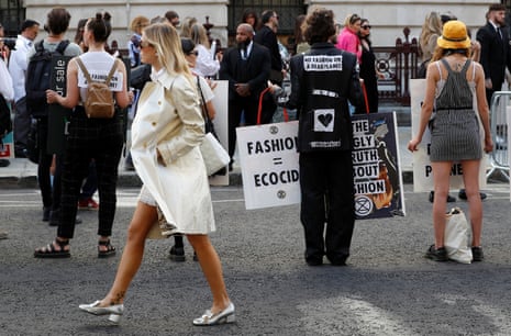 A show-goer walks past Extinction Rebellion protesters as they demonstrate against London fashion week.