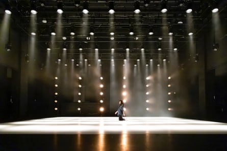 Sung Im Her stands alone on a vast stage lit by a grid of bulbs in 1 Degree Celsius