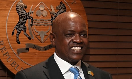 Mokgweetsi Masisi smiles in front of a plaque bearing Botswana's coat of arms