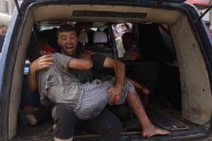 A man carries a wounded child in the back of a van