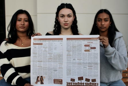 Three high school students hold up a newspaper