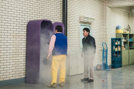 Still from the show shows two middle-aged men in what looks like quite a clean industrial workplace staring at a purple wardrobe that is open and from which smoke is emanating.