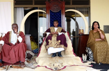 King Oyo Nyimba, aged 13, sits on a throne between his mother Best Kemigisha and an unidentified man
